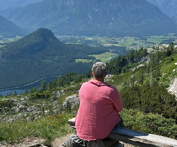Eine Frau blickt von einem Berg hinab ins Tal